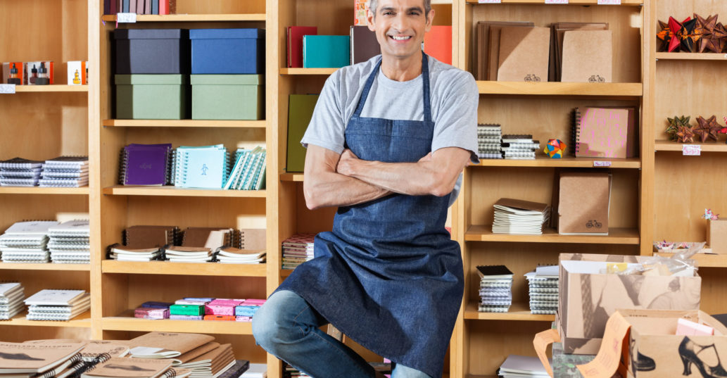 A seasonal small bookstore business owner smiling in his shop.