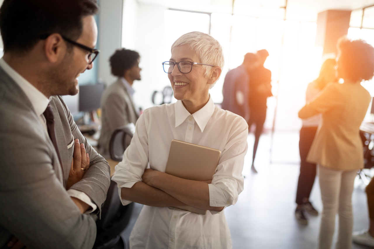 photo of woman in white shirt smiling at man in gray suit at a social gathering